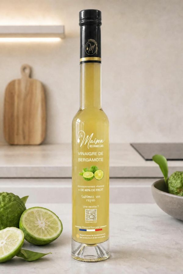 Bouteille de vinaigre de bergamote La Maison Des Grands Lacs entourée de bergamotes sur un plan de travail